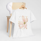 A white t-shirt hanging on a chair, featuring a graphic design of a pink bloom surrounded by bunnies in various poses.