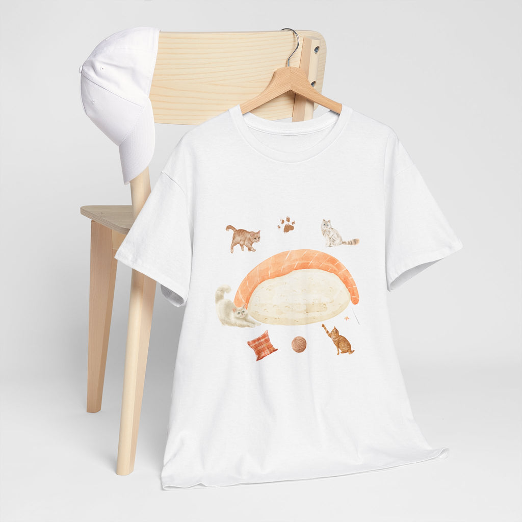 A white t-shirt hanging on a chair, featuring a graphic design of a piece of nigiri sushi surrounded by a circle of cats, yarn balls, and cushions.
