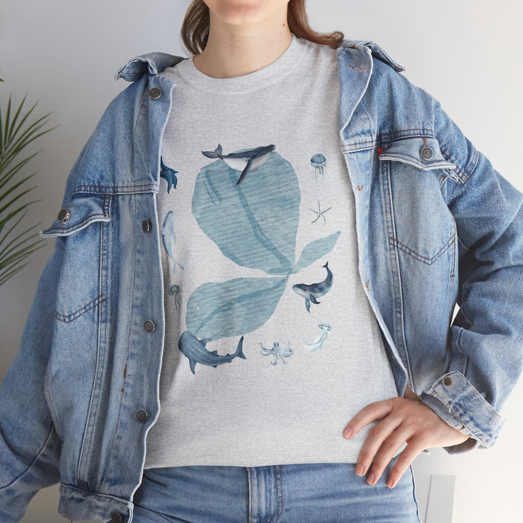 A girl wearing a denim jacket over a grey t-shirt featuring a colorful design of a blue bloom surrounded by whales, jellyfish, and starfish.