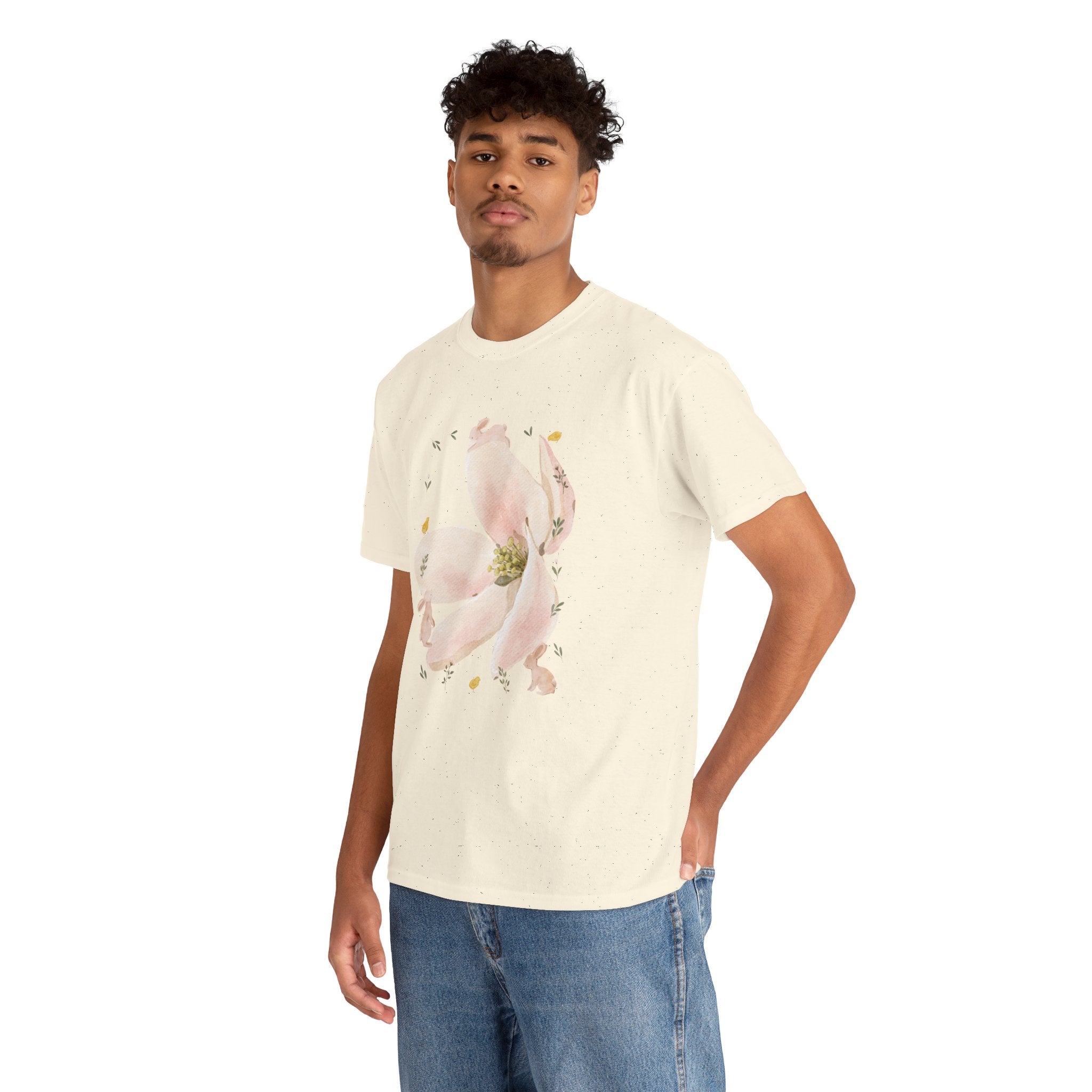 A man wearing a beige t-shirt featuring a graphic design of a pink bloom surrounded by bunnies in various poses.