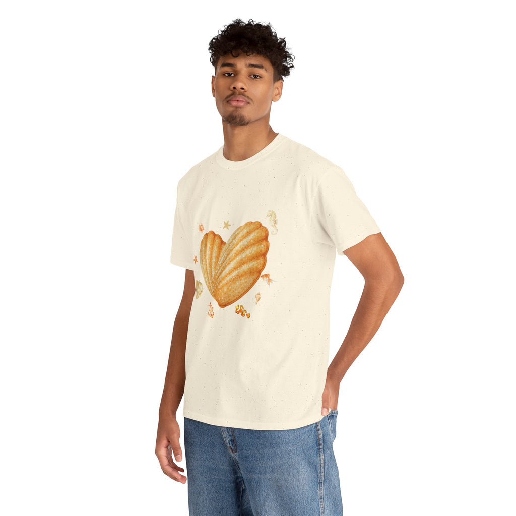 A man wearing a beige t-shirt featuring a graphic design of a heart-shaped madeleine surrounded by yellow tropical fish, starfish, seahorses, and coral.