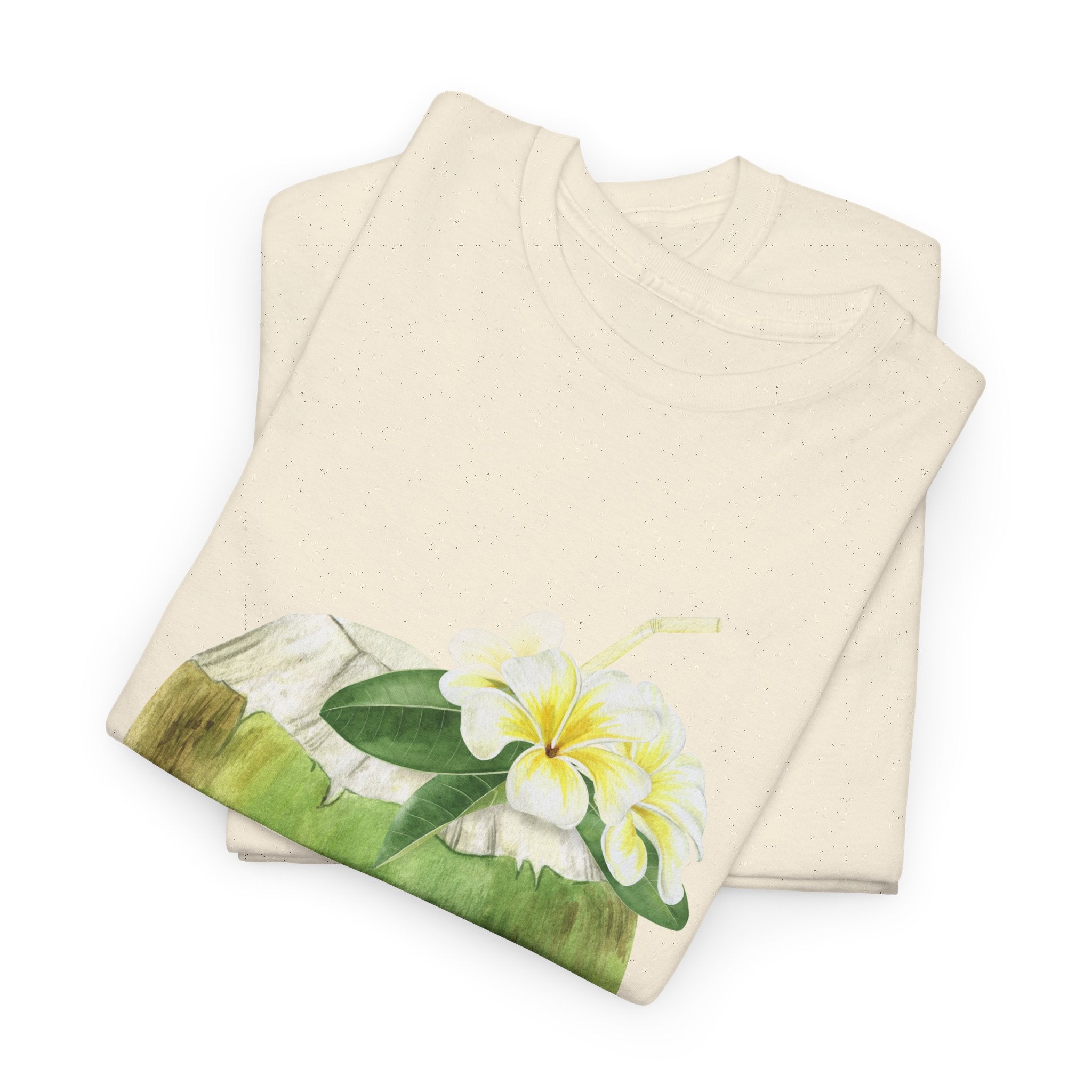 A folded beige t-shirt featuring a graphic design of a hermit crab in a coconut shell and a straw-topped coconut.
