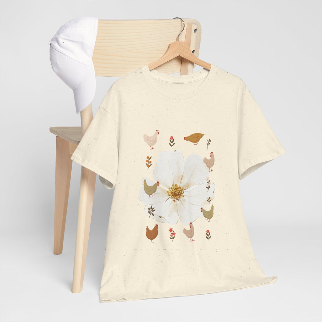 A beige t-shirt hanging on a chair, featuring a graphic design of a bloom surrounded by roosters in various poses.