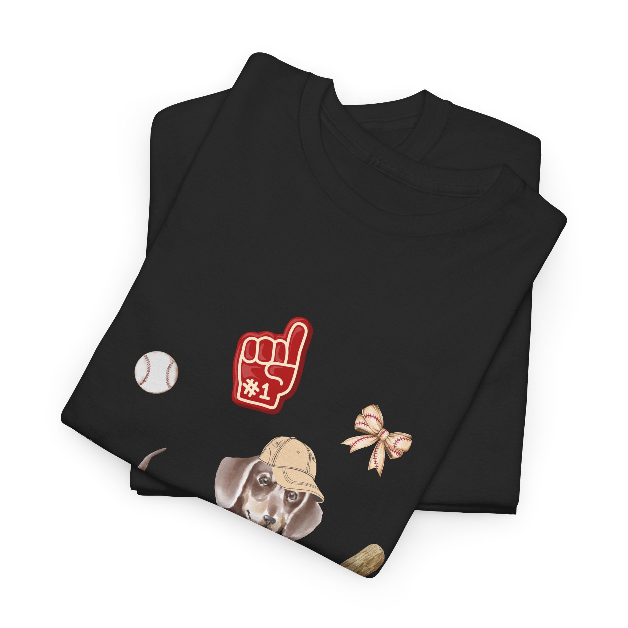 A folded black t-shirt featuring a graphic design of a dog in a baseball hat surrounded by a circle of balls, bats, and helmets.
