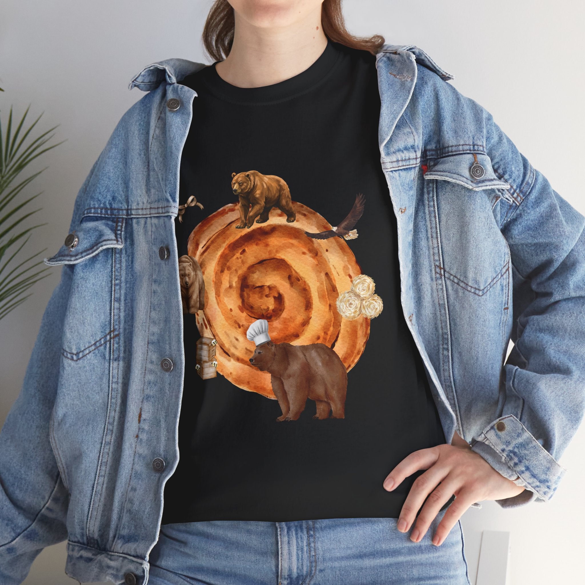 A girl wearing a denim jacket over a black t-shirt featuring a colorful design of a cinnamon roll surrounded by several hungry bears.
