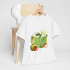 A white t-shirt hanging on a chair, featuring a graphic design of a hermit crab in a coconut shell and a straw-topped coconut.