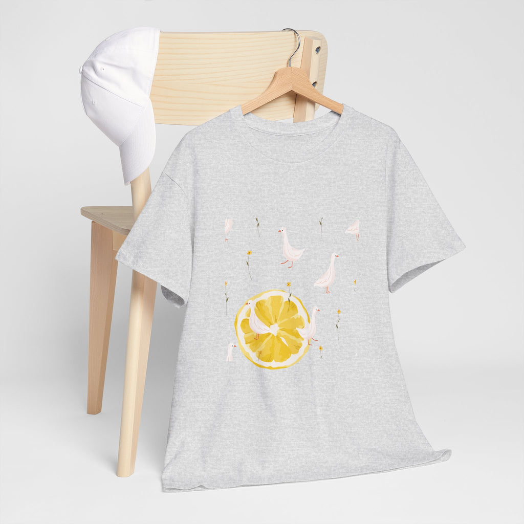 A grey t-shirt hanging on a chair, featuring a graphic design of white ducks across the whole shirt and a juicy lemon in the bottom-left corner.