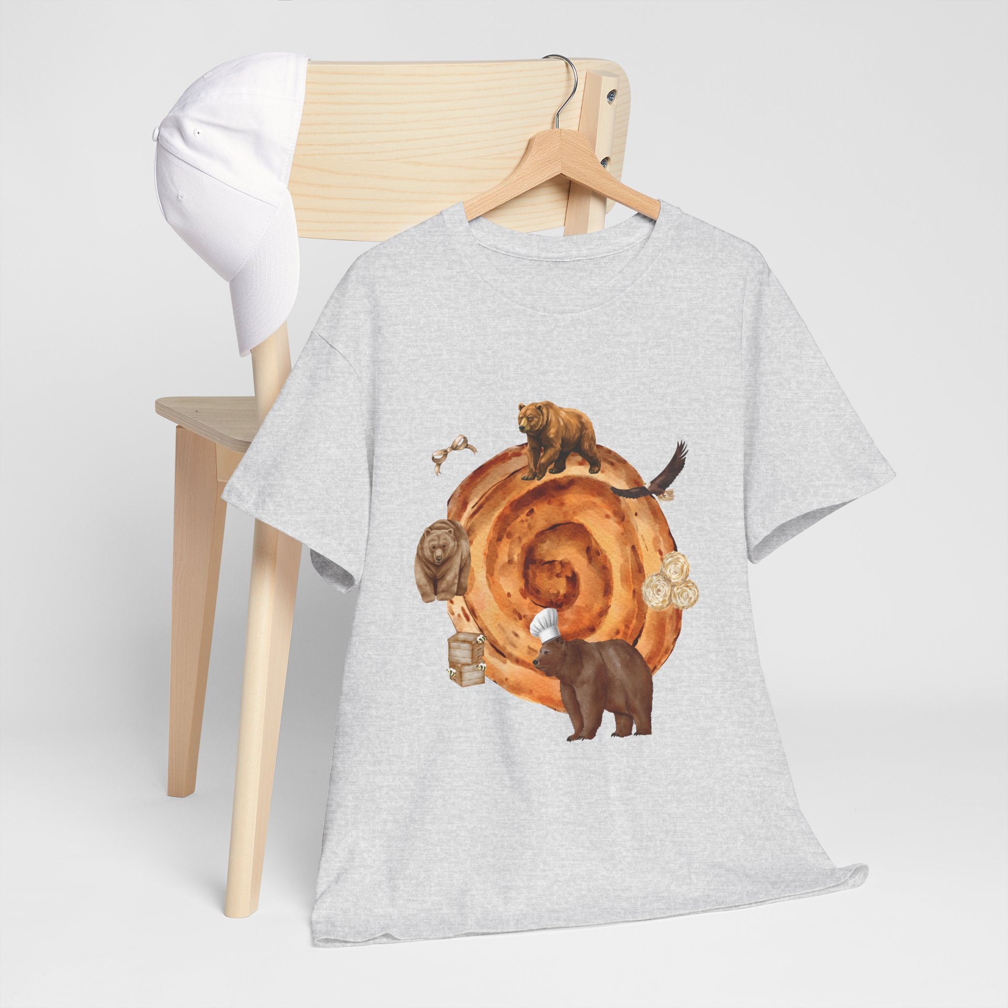 A grey t-shirt hanging on a chair, featuring a graphic design of a cinnamon roll surrounded by several hungry bears.