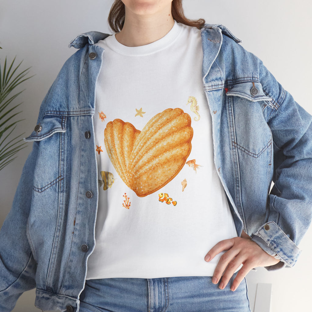 A girl wearing a denim jacket over a white t-shirt featuring a colorful design of a heart-shaped madeleine surrounded by yellow tropical fish, starfish, seahorses, and coral.
