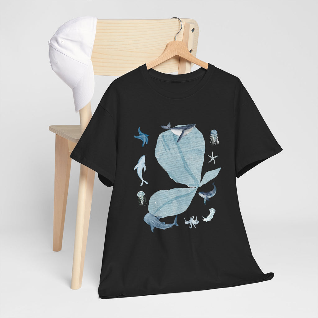 A black t-shirt hanging on a chair, featuring a graphic design of a blue bloom surrounded by whales, jellyfish, and starfish.