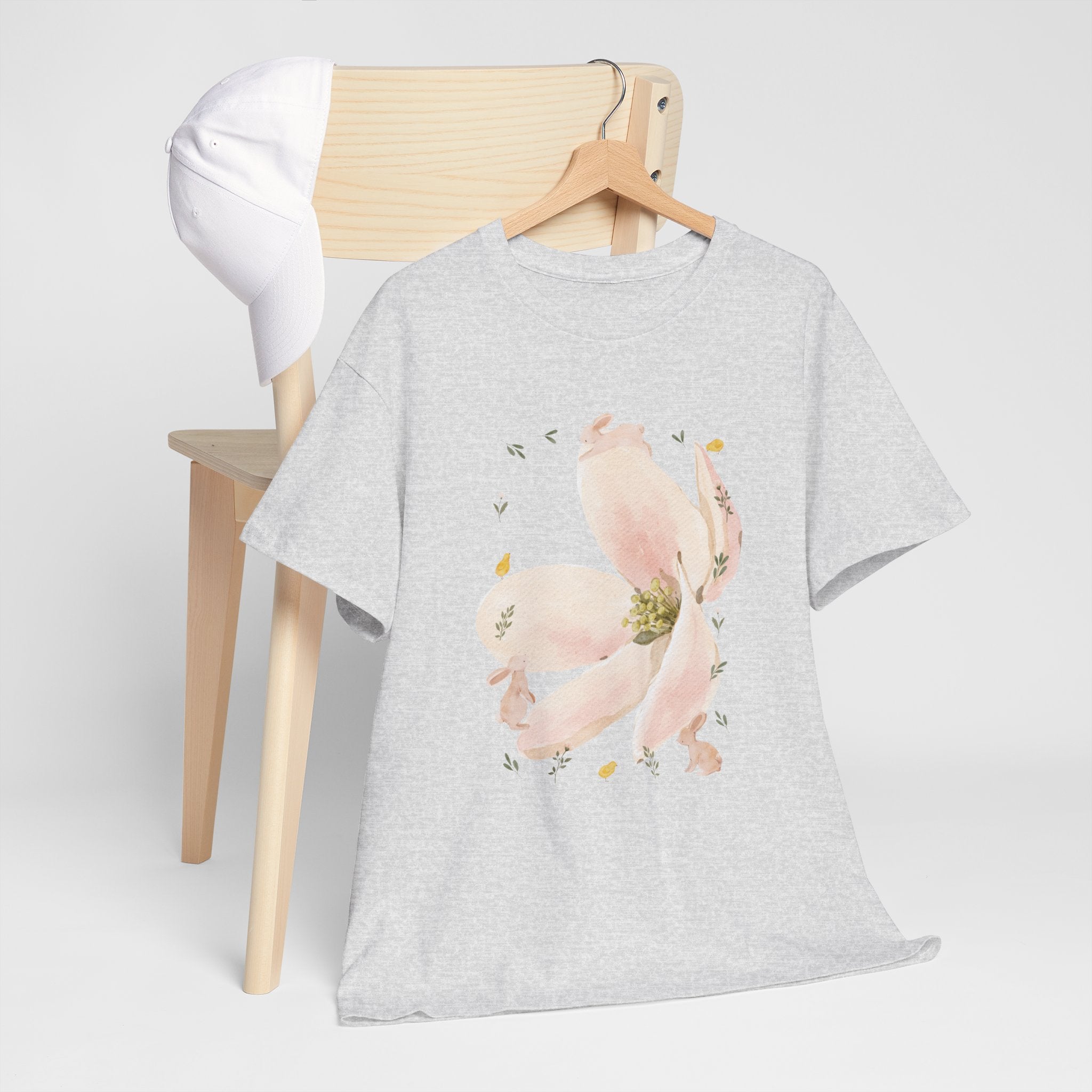 A grey t-shirt hanging on a chair, featuring a graphic design of a pink bloom surrounded by bunnies in various poses.