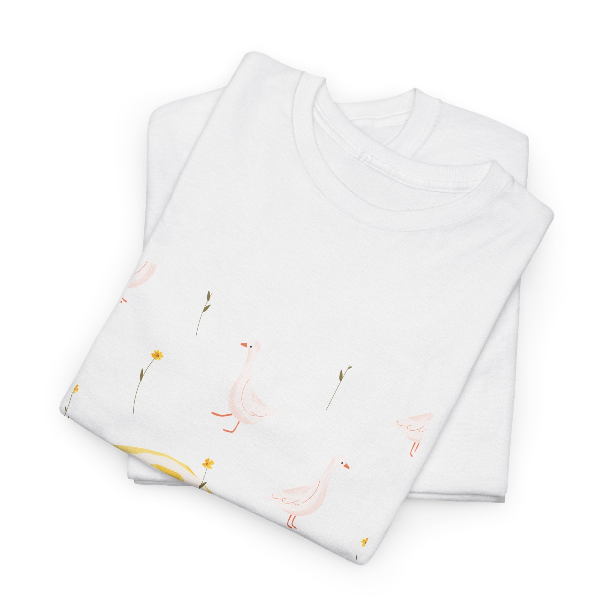 A folded white t-shirt featuring a graphic design of white ducks all over, with a juicy lemon in the bottom-left corner.
