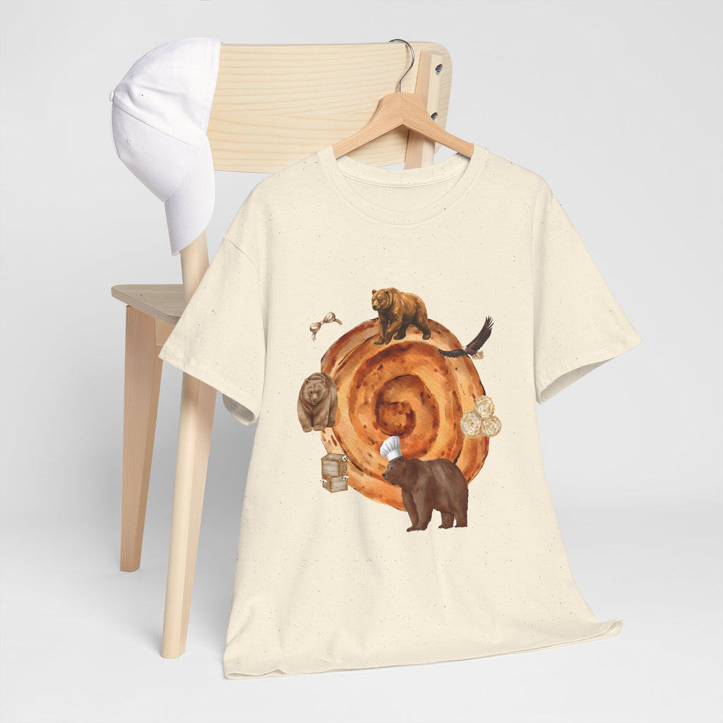 A beige t-shirt hanging on a chair, featuring a graphic design of a cinnamon roll surrounded by several hungry bears.