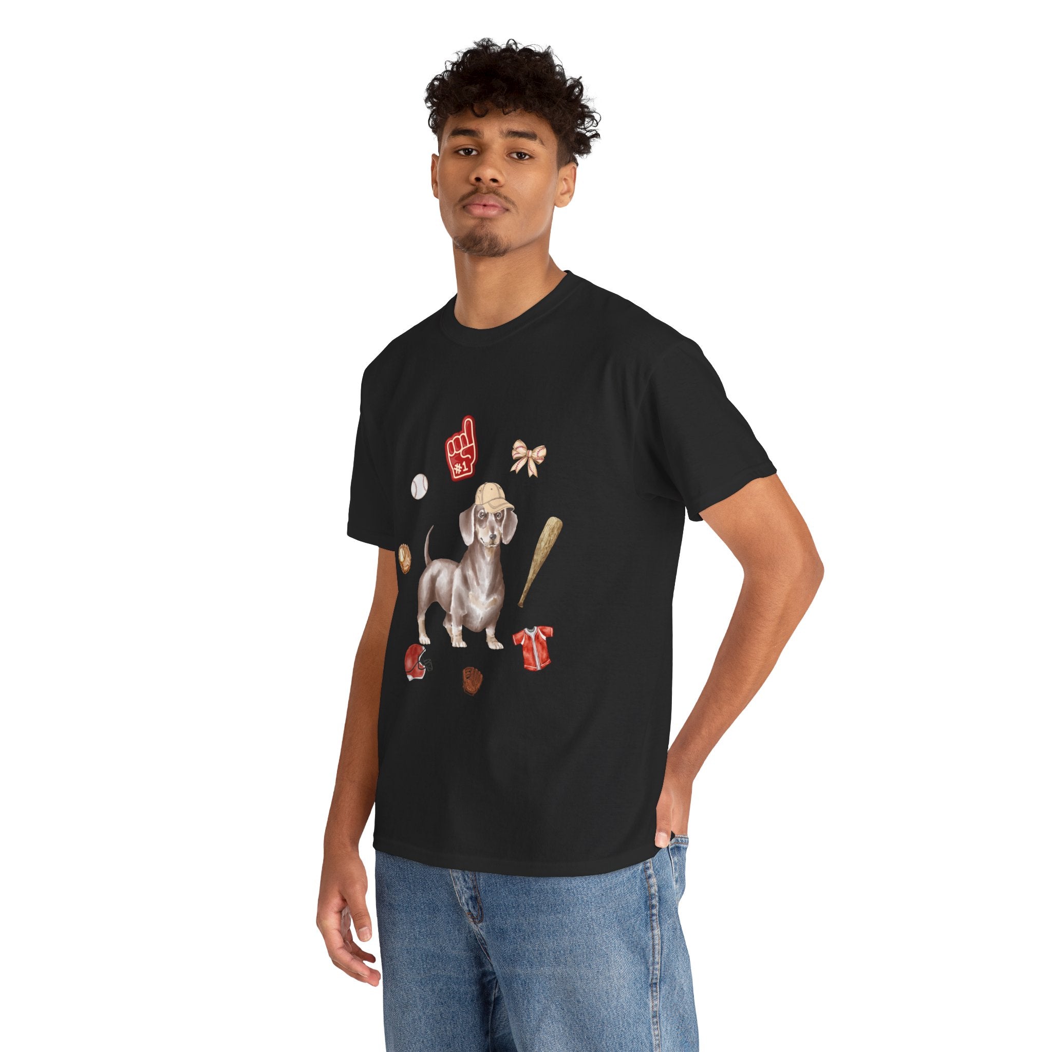 A man wearing a black t-shirt featuring a graphic design of a dog in a baseball hat surrounded by a circle of balls, bats, and helmets.