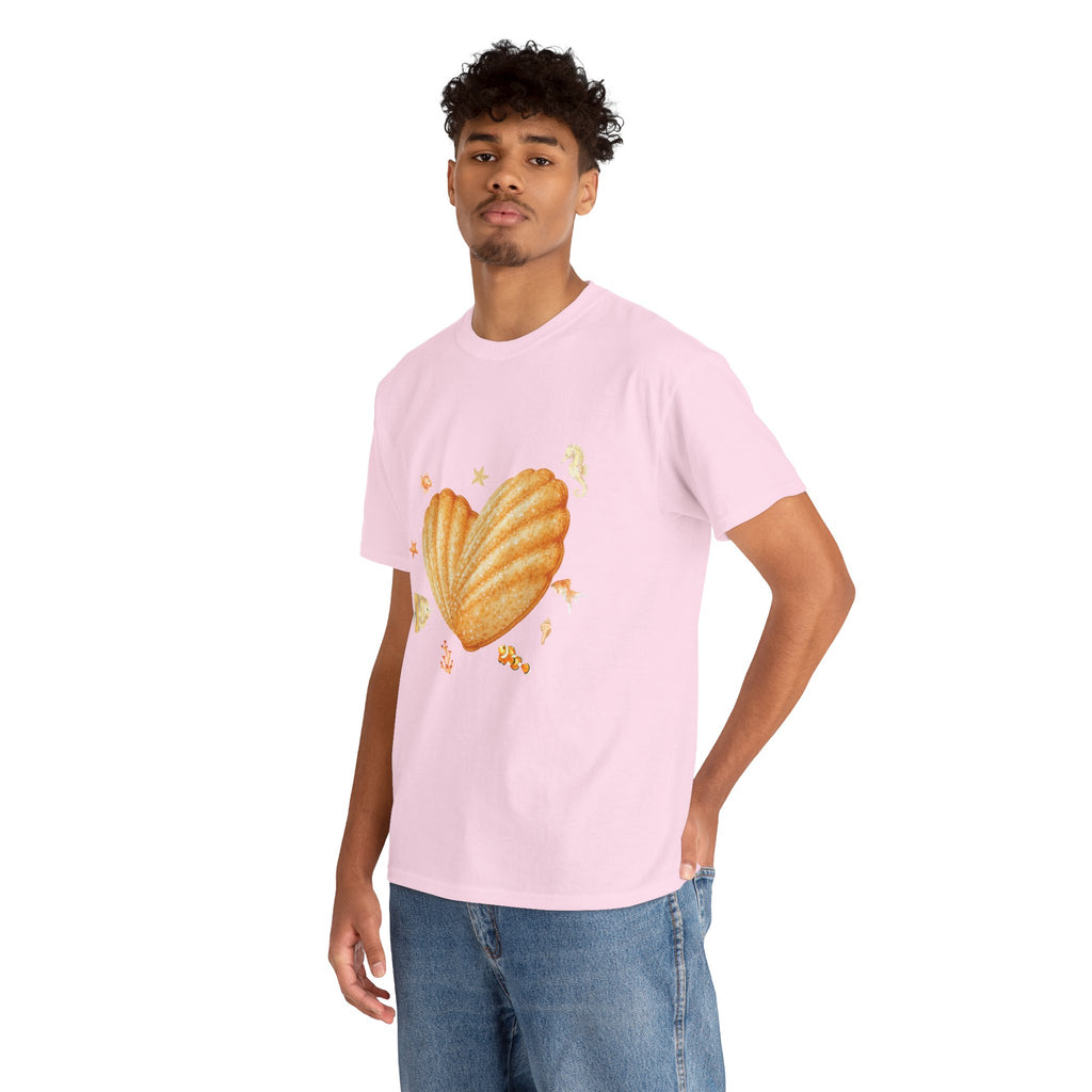 A man wearing a pink t-shirt featuring a graphic design of a heart-shaped madeleine surrounded by yellow tropical fish, starfish, seahorses, and coral.