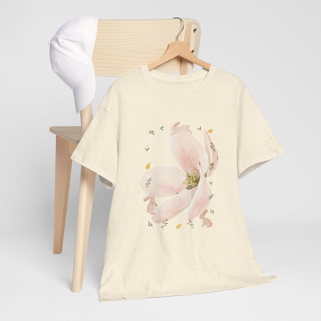 A beige t-shirt hanging on a chair, featuring a graphic design of a pink bloom surrounded by bunnies in various poses.