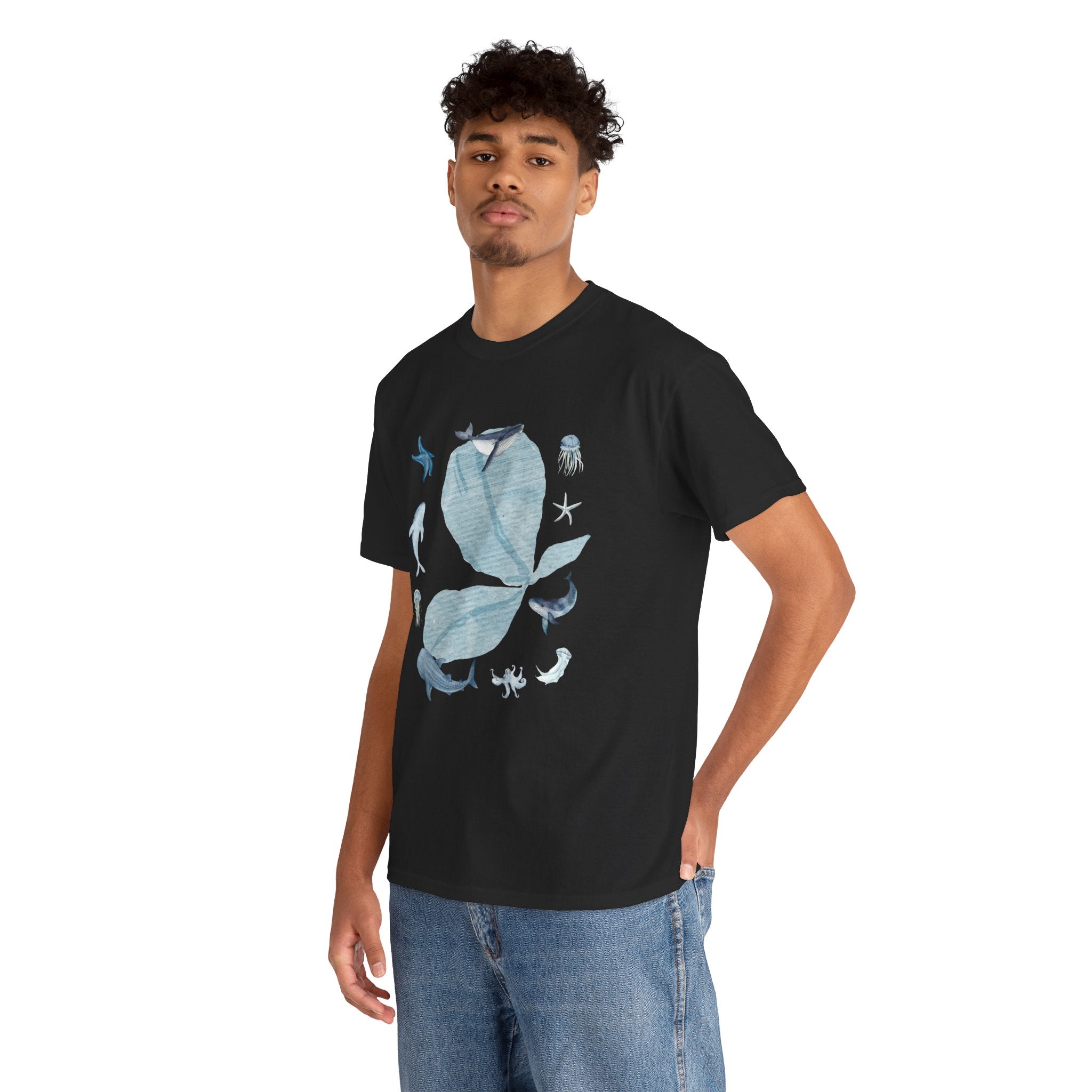 A man wearing a black t-shirt featuring a graphic design of a blue bloom surrounded by whales, jellyfish, and starfish.