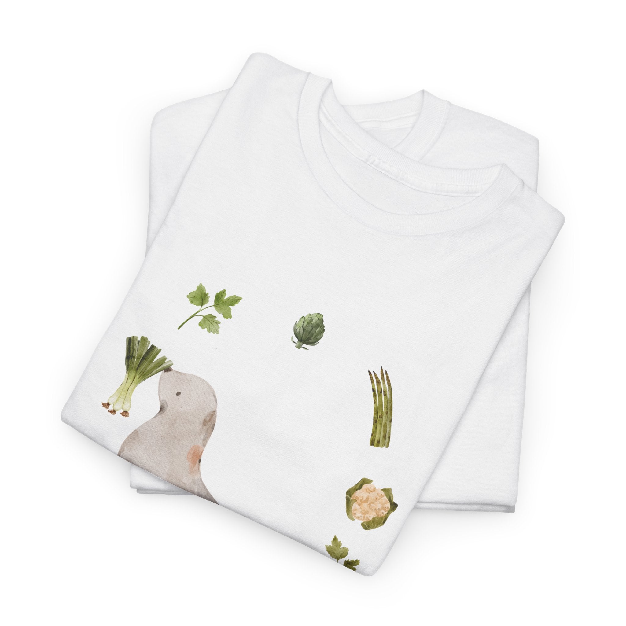 A folded white t-shirt featuring a graphic design of a sea lion surrounded by green onions, cabbage, and broccoli.