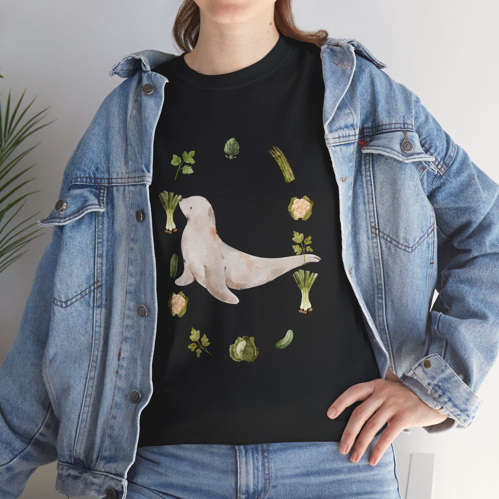 A girl wearing a denim jacket over a black t-shirt featuring a colorful design of a sea lion surrounded by green onions, cabbage, and broccoli.