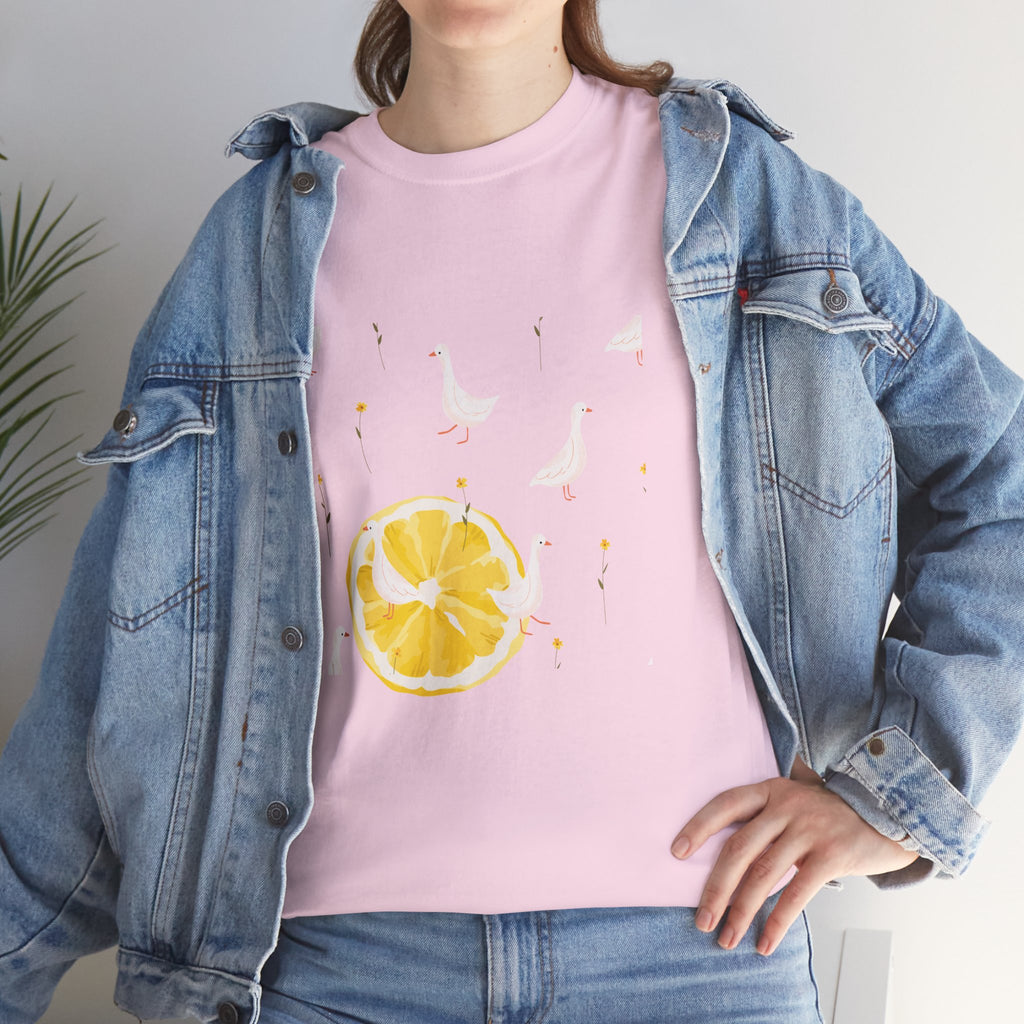 A girl wearing a denim jacket over a pink t-shirt featuring a colorful design of white ducks covering the shirt with a juicy lemon in the bottom-left corner.