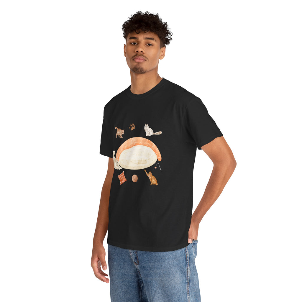A man wearing a black t-shirt featuring a graphic design of a piece of nigiri sushi surrounded by a circle of cats, yarn balls, and cushions.