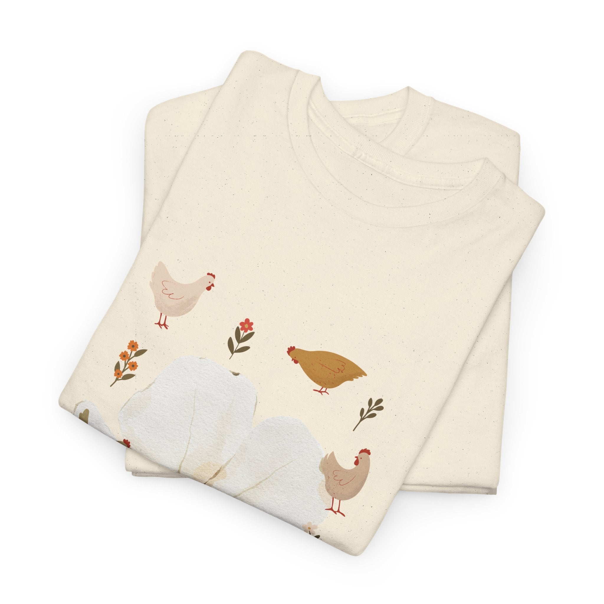 A folded beige t-shirt featuring a graphic design of a bloom surrounded by roosters in various poses.