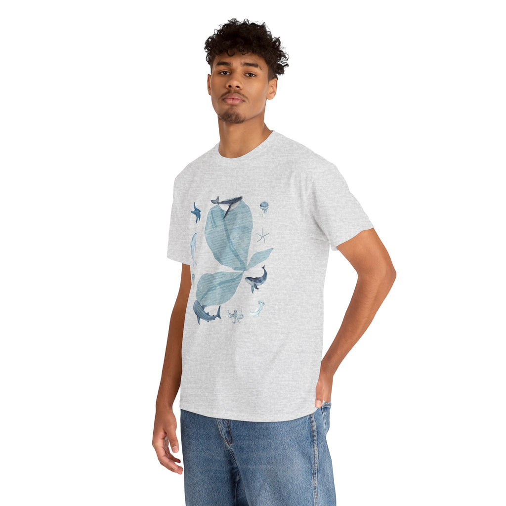 A man wearing a grey t-shirt featuring a graphic design of a blue bloom surrounded by whales, jellyfish, and starfish.