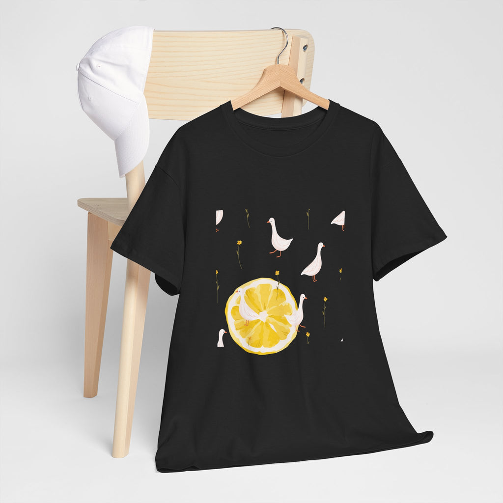A black t-shirt hanging on a chair, featuring a graphic design of white ducks across the whole shirt and a juicy lemon in the bottom-left corner.