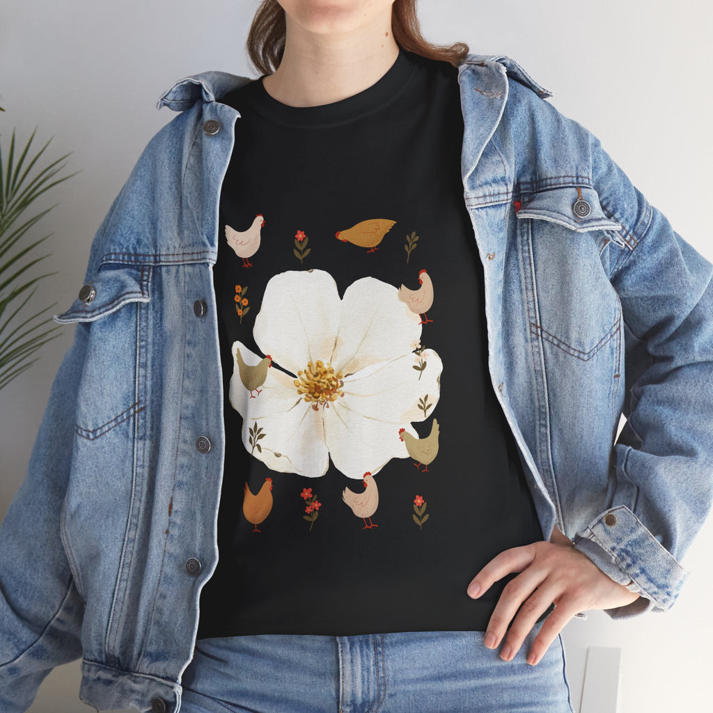 A girl wearing a denim jacket over a black t-shirt featuring a colorful design of a bloom surrounded by roosters in various poses.