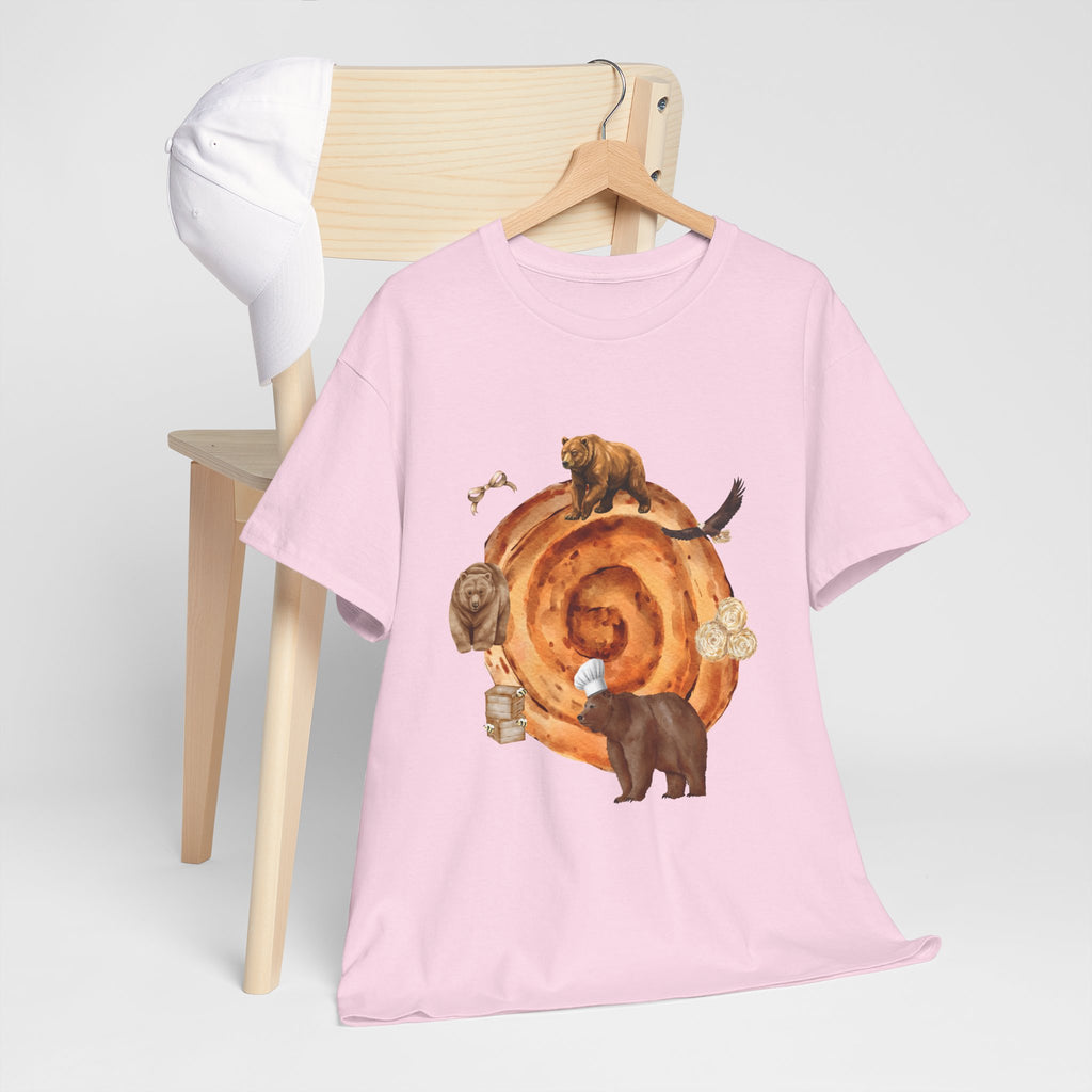 A pink t-shirt hanging on a chair, featuring a graphic design of a cinnamon roll surrounded by several hungry bears.