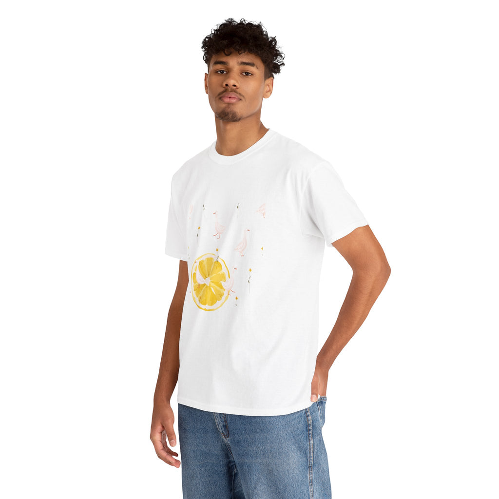 A man wearing a white t-shirt featuring a graphic design of white ducks throughout the print and a juicy lemon in the bottom-left corner.