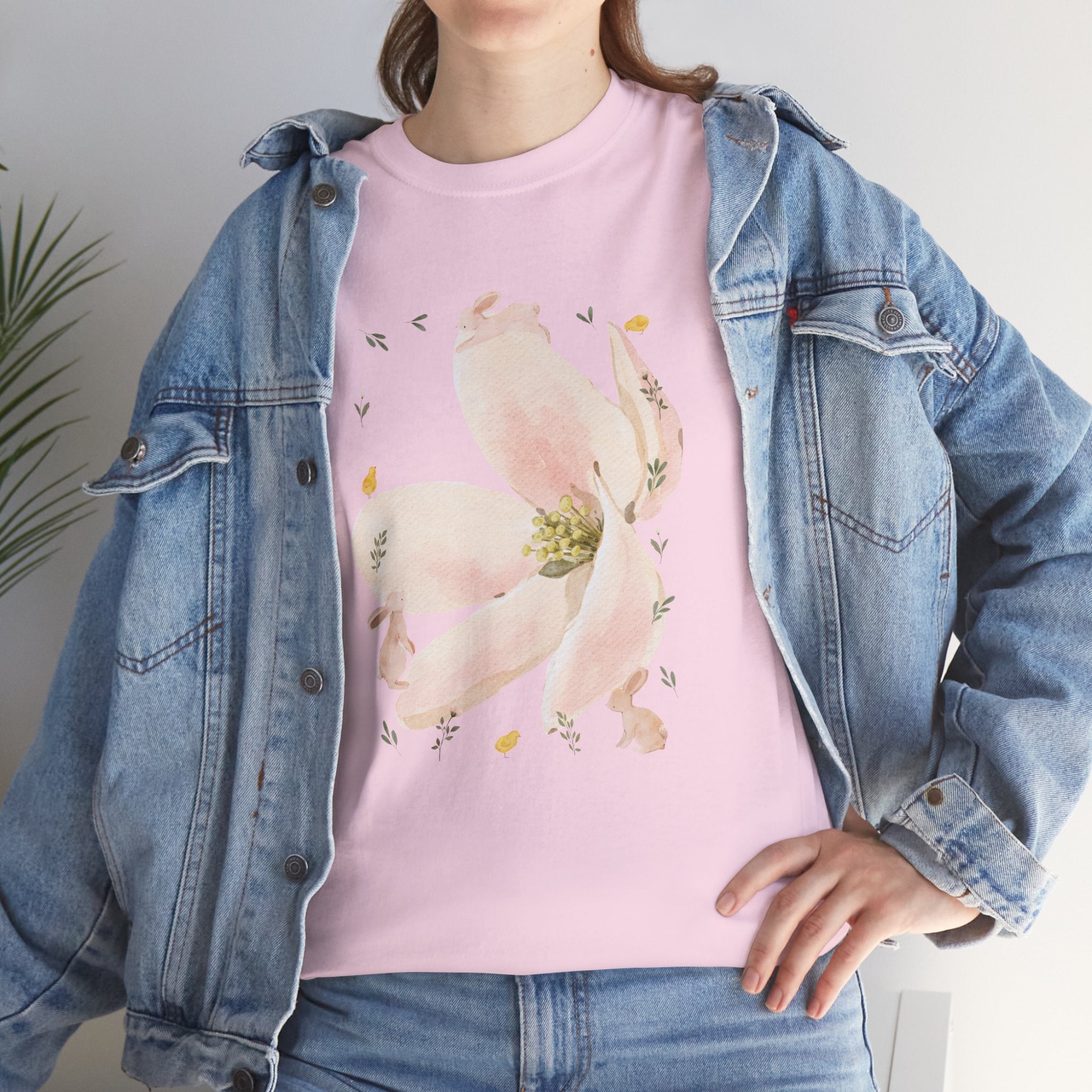 A girl wearing a denim jacket over a pink t-shirt featuring a colorful design of a pink bloom surrounded by bunnies in various poses.