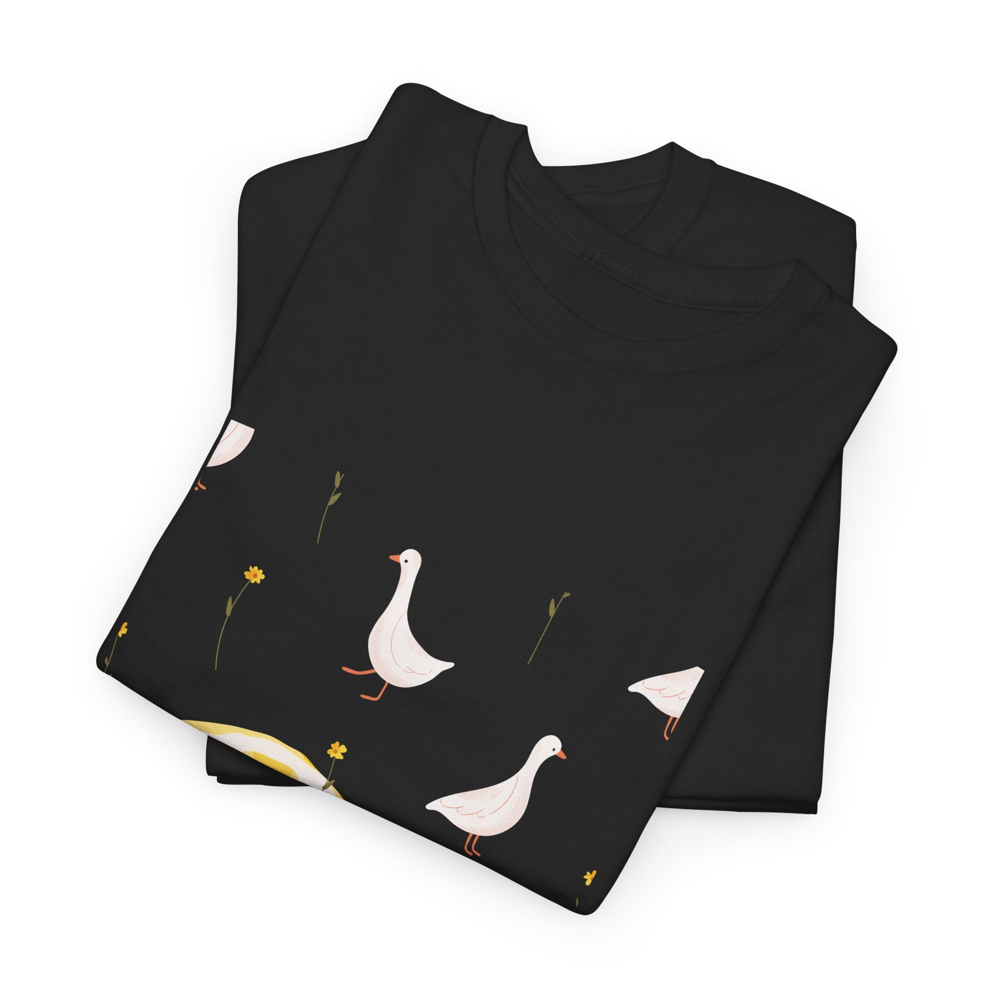 A folded black t-shirt featuring a graphic design of white ducks all over, with a juicy lemon in the bottom-left corner.