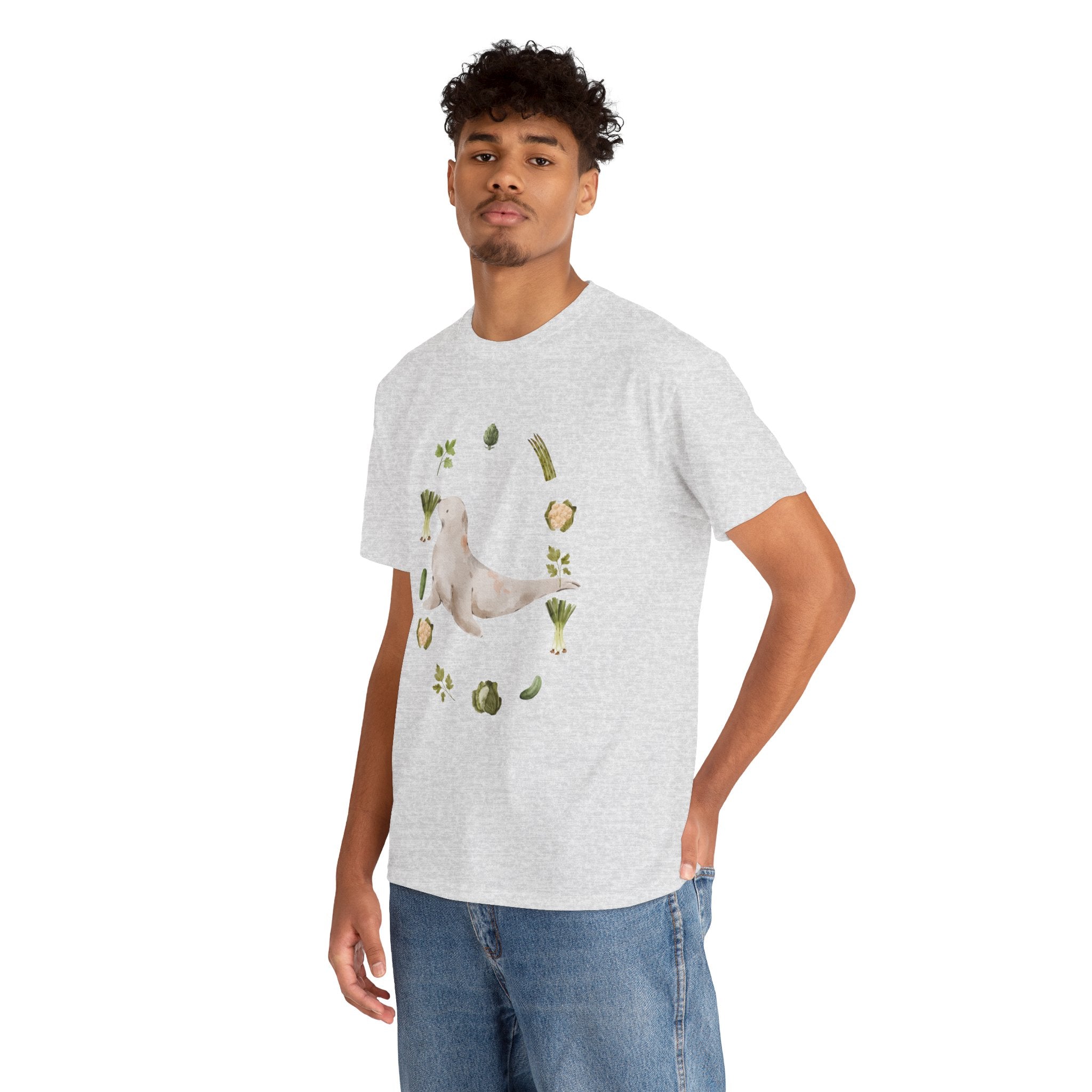 A man wearing a grey t-shirt featuring a graphic design of a sea lion surrounded by green onions, cabbage, and broccoli.