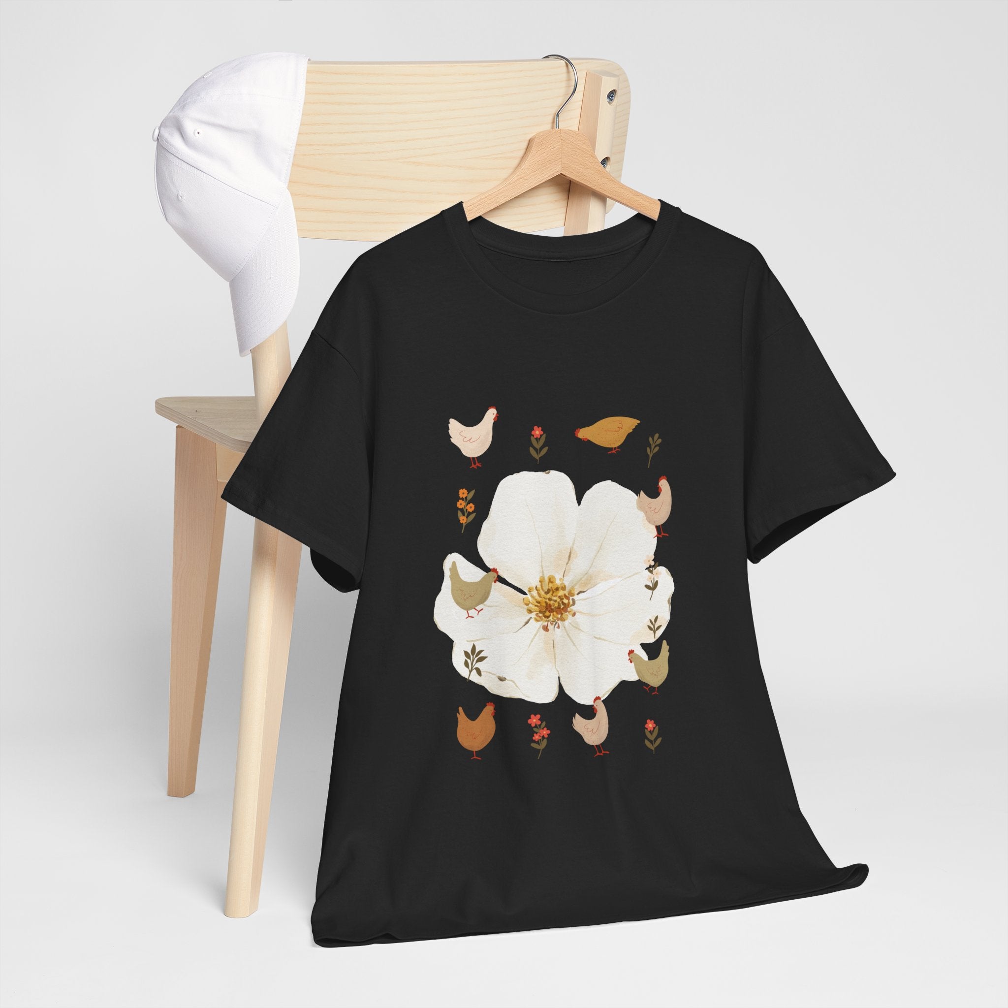 A black t-shirt hanging on a chair, featuring a graphic design of a bloom surrounded by roosters in various poses.