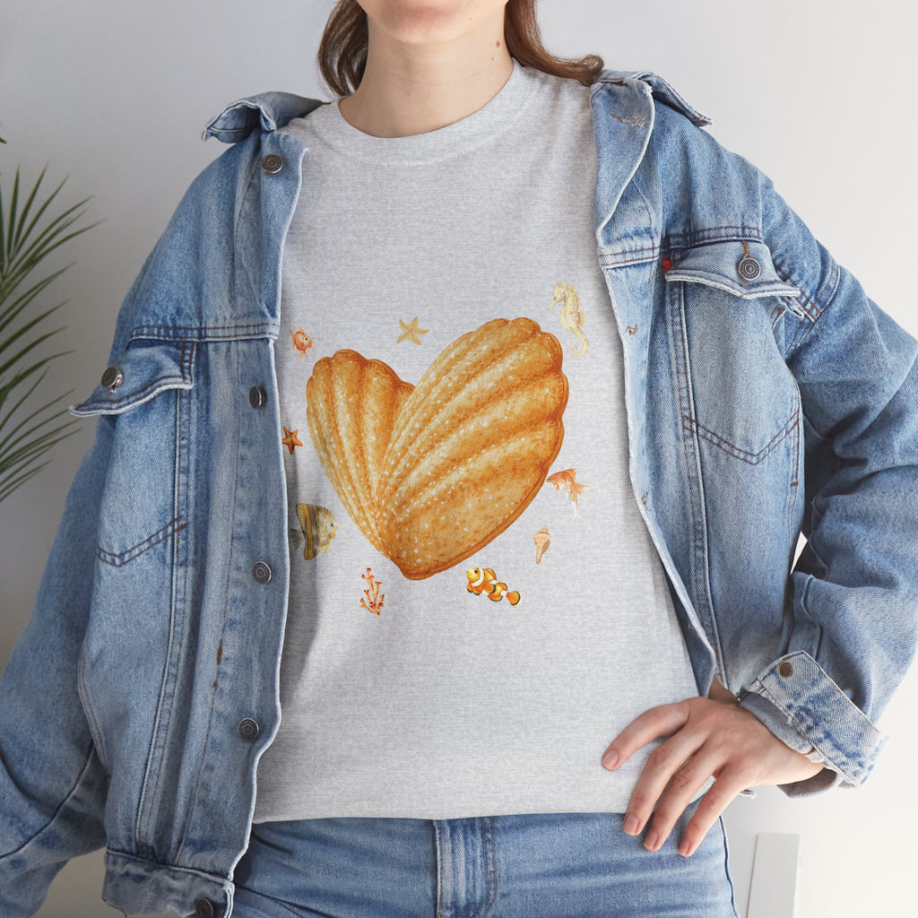 A girl wearing a denim jacket over a grey t-shirt featuring a colorful design of a heart-shaped madeleine surrounded by yellow tropical fish, starfish, seahorses, and coral.