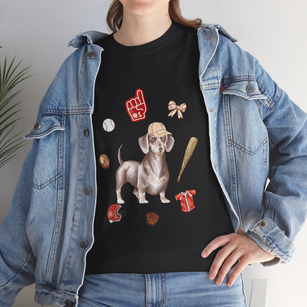 A girl wearing a denim jacket over a black t-shirt featuring a colorful design of a dog in a baseball hat surrounded by a circle of balls, bats, and helmets.