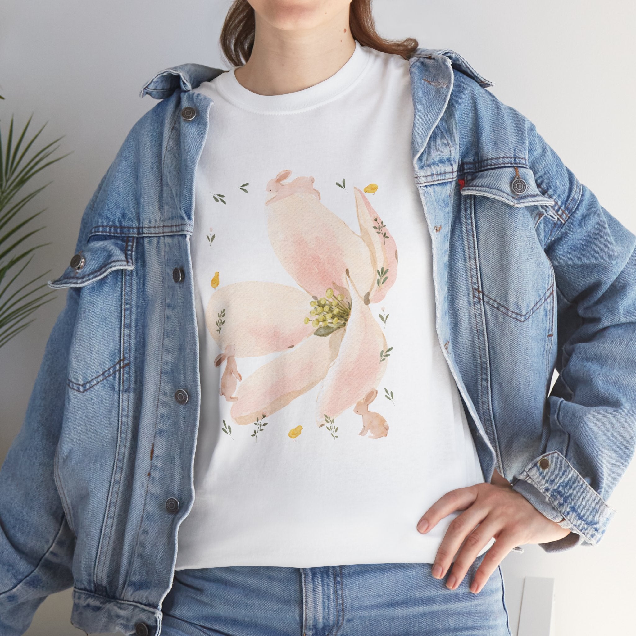 A girl wearing a denim jacket over a white t-shirt featuring a colorful design of a pink bloom surrounded by bunnies in various poses.