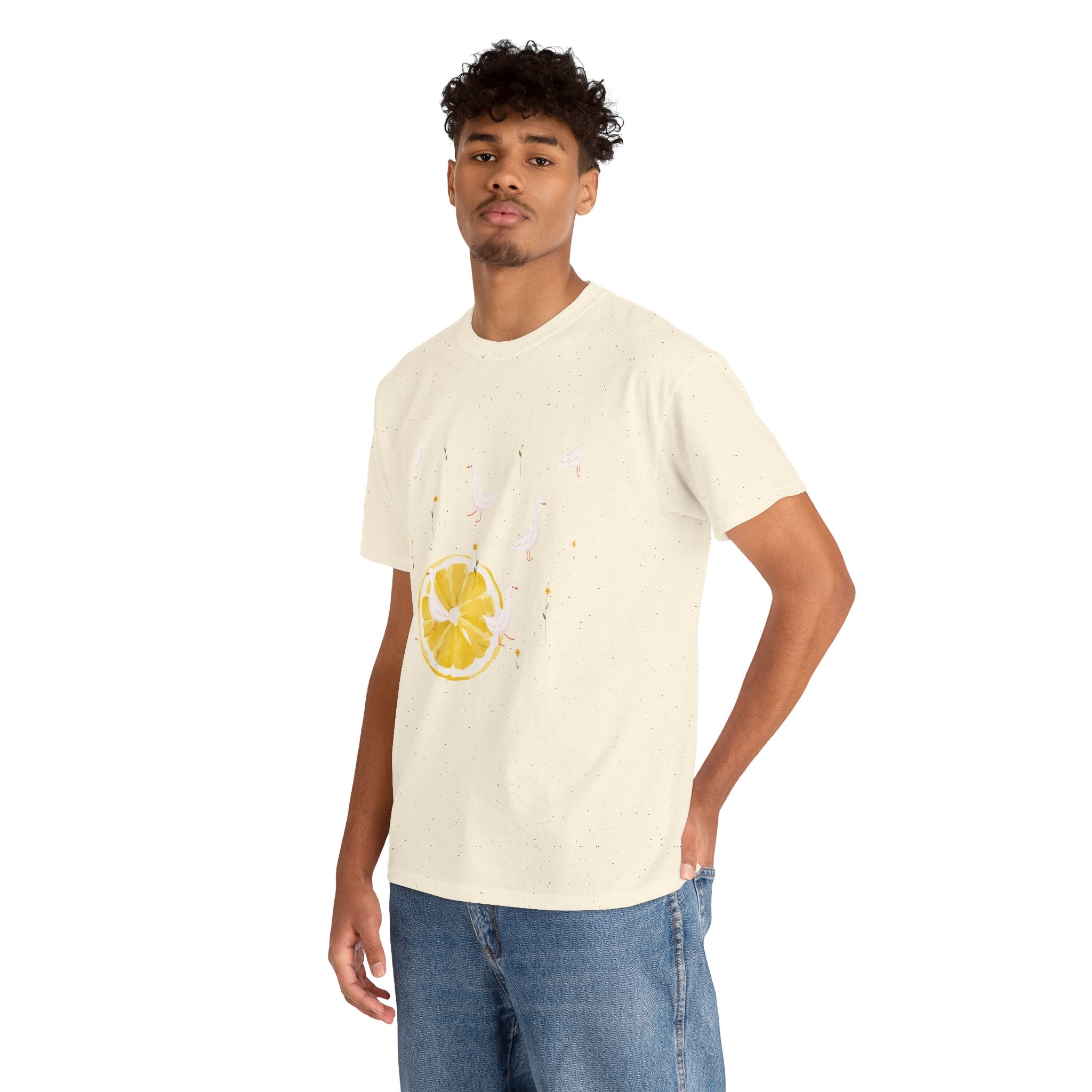 A man wearing a beige t-shirt featuring a graphic design of white ducks throughout the print and a juicy lemon in the bottom-left corner.