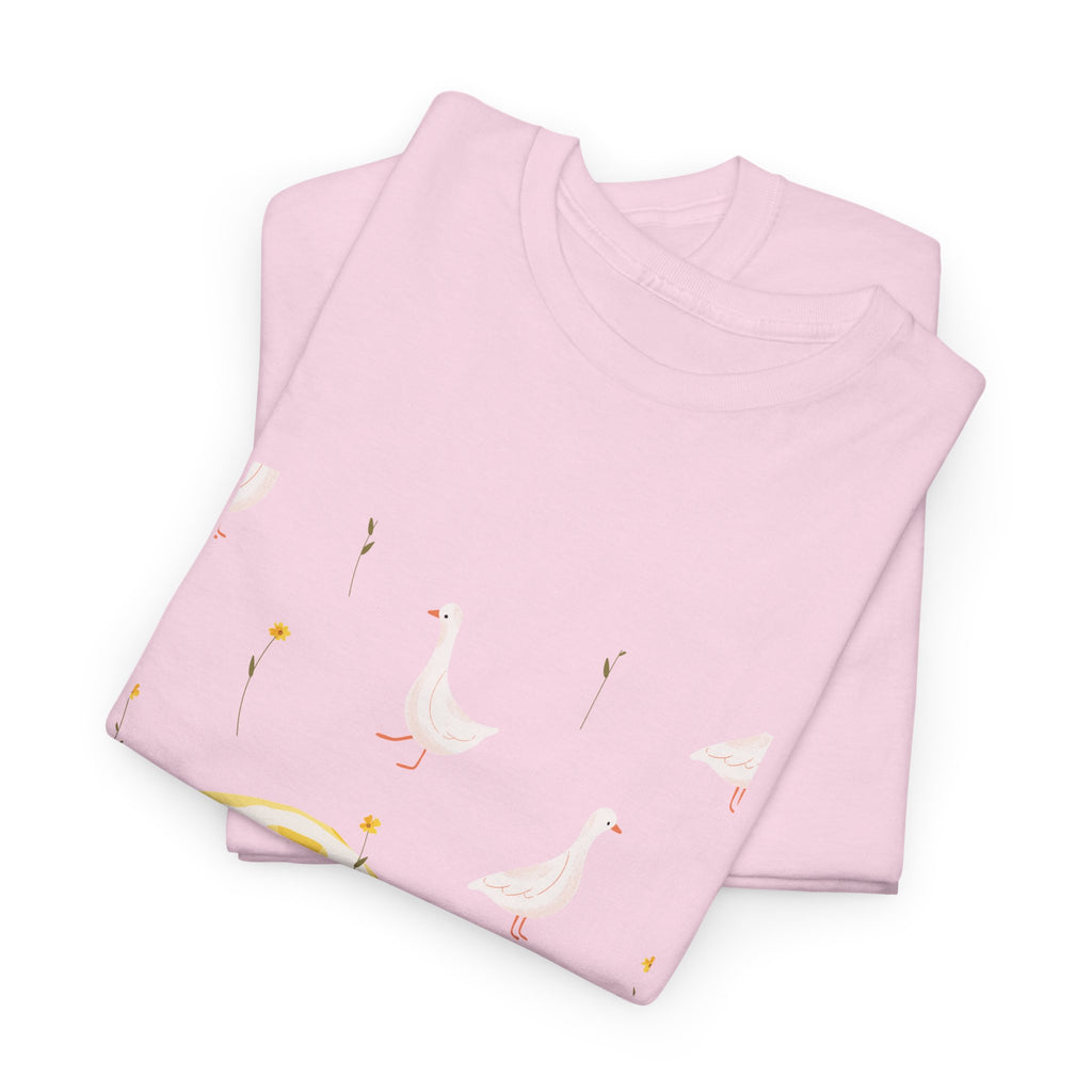 A folded pink t-shirt featuring a graphic design of white ducks all over, with a juicy lemon in the bottom-left corner.