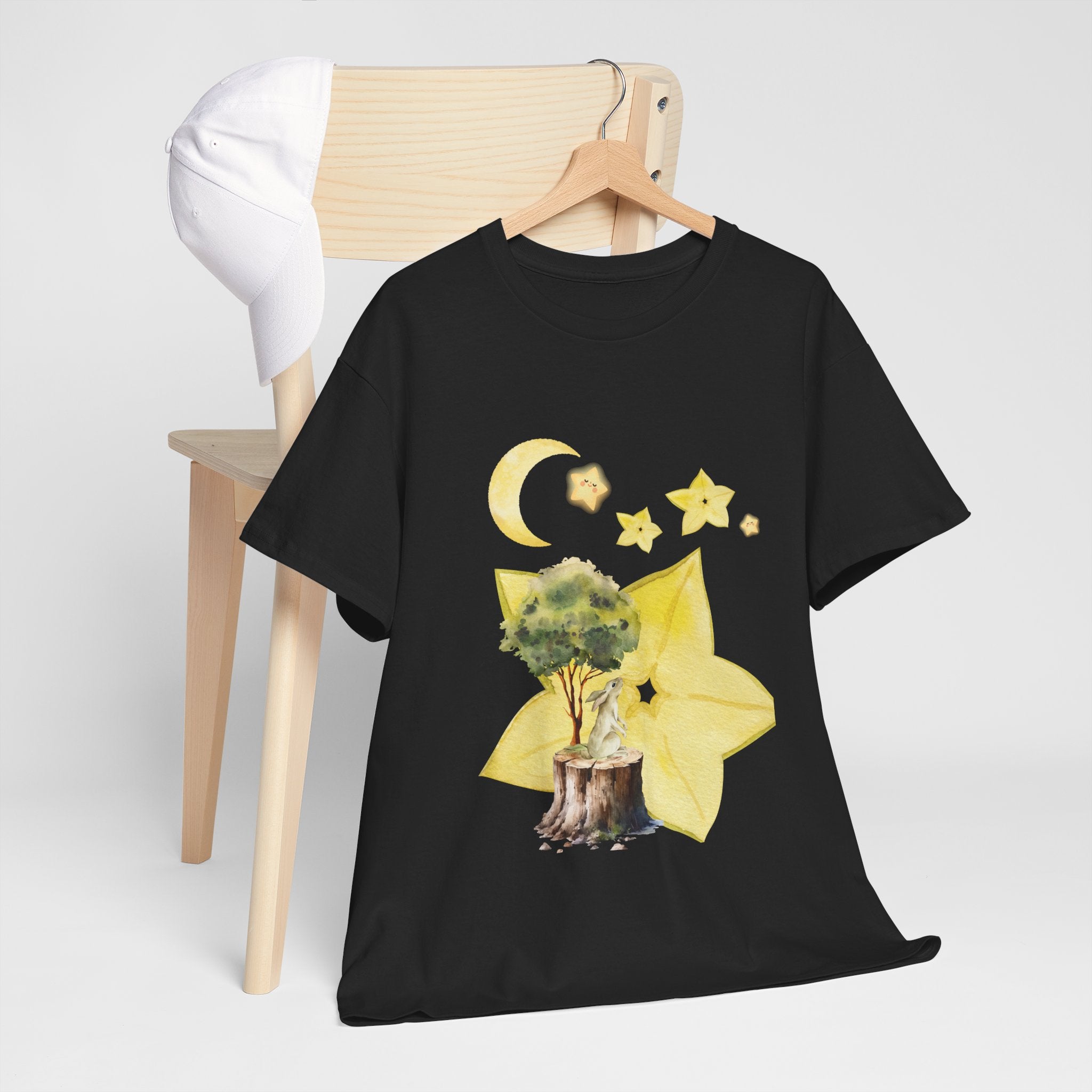 A black t-shirt hanging on a chair, featuring a graphic design of a tree stump, leaves, and starfruit celestial elements.