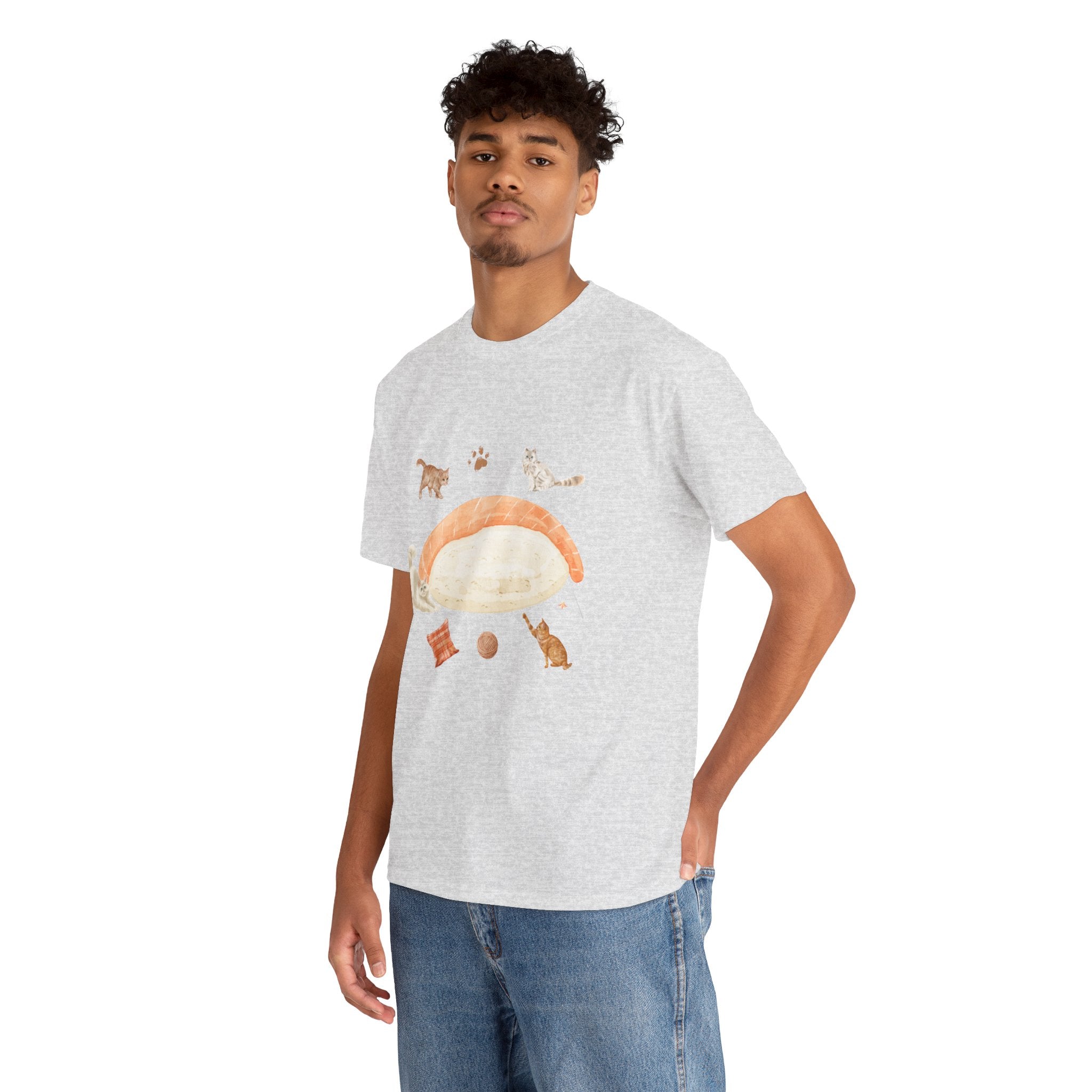 A man wearing a grey t-shirt featuring a graphic design of a piece of nigiri sushi surrounded by a circle of cats, yarn balls, and cushions.