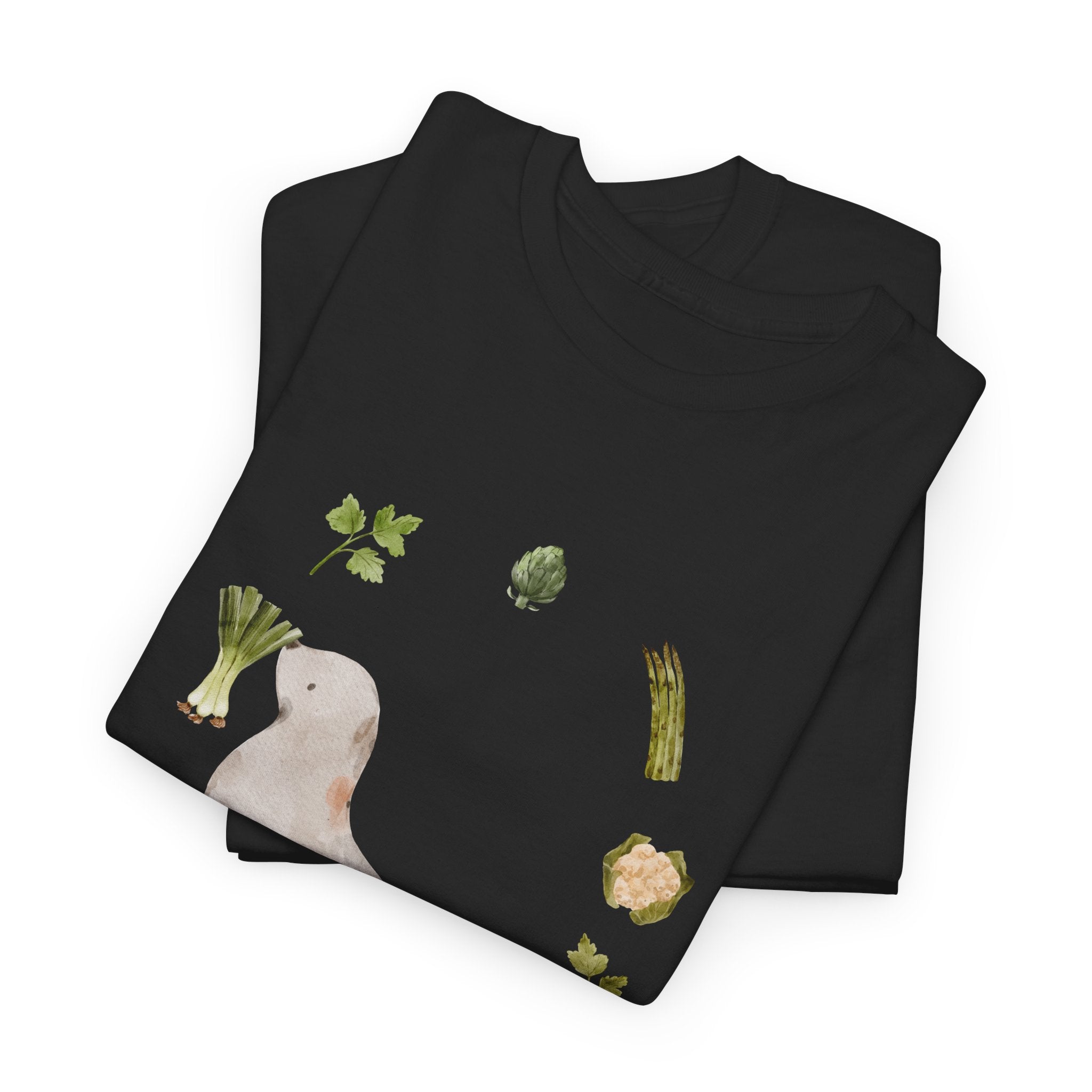 A folded black t-shirt featuring a graphic design of a sea lion surrounded by green onions, cabbage, and broccoli.