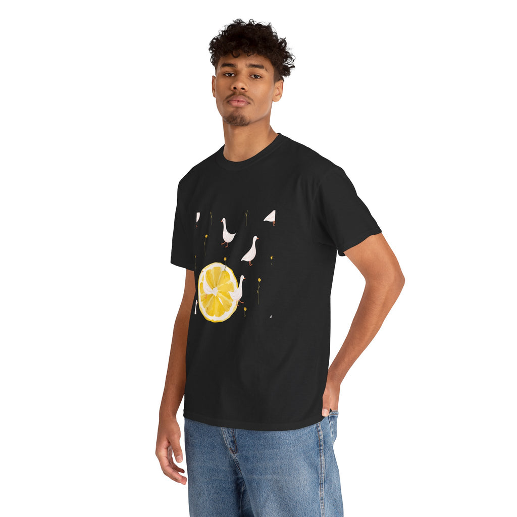 A man wearing a black t-shirt featuring a graphic design of white ducks throughout the print and a juicy lemon in the bottom-left corner.