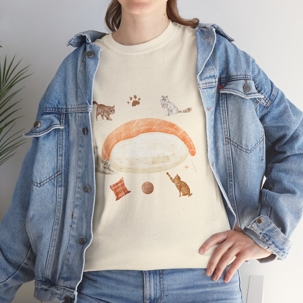 A girl wearing a denim jacket over a beige t-shirt featuring a colorful design of a piece of nigiri sushi surrounded by a circle of cats, yarn balls, and cushions.