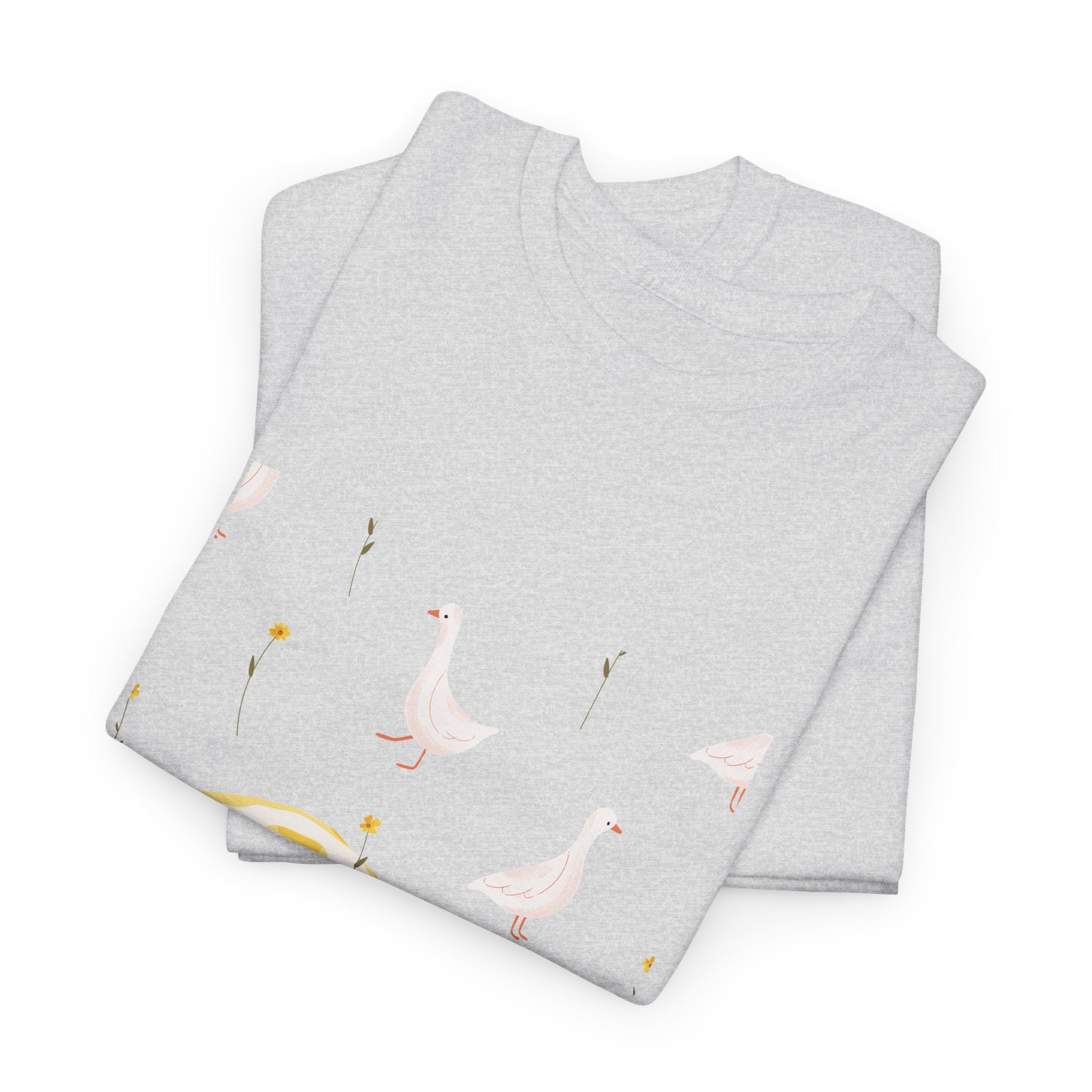 A folded grey t-shirt featuring a graphic design of white ducks all over, with a juicy lemon in the bottom-left corner.
