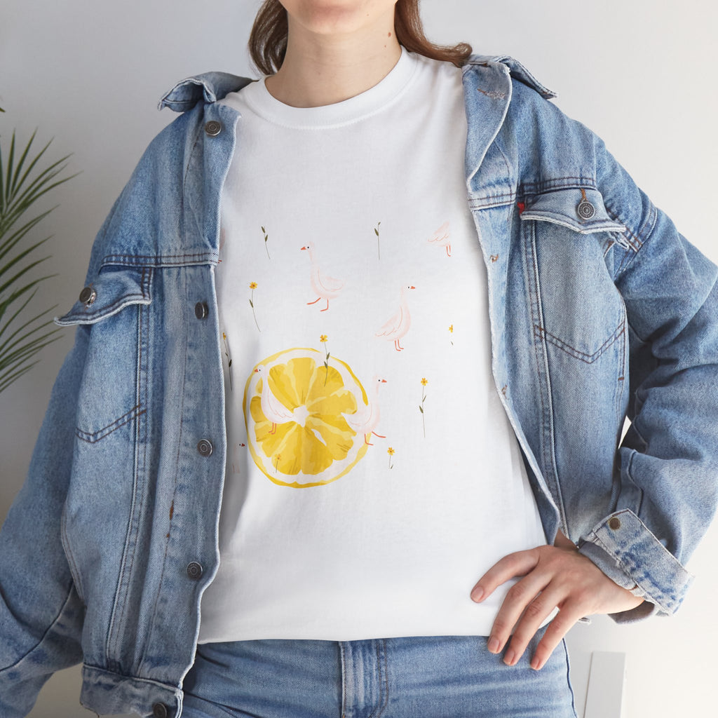A girl wearing a denim jacket over a white t-shirt featuring a colorful design of white ducks covering the shirt with a juicy lemon in the bottom-left corner.