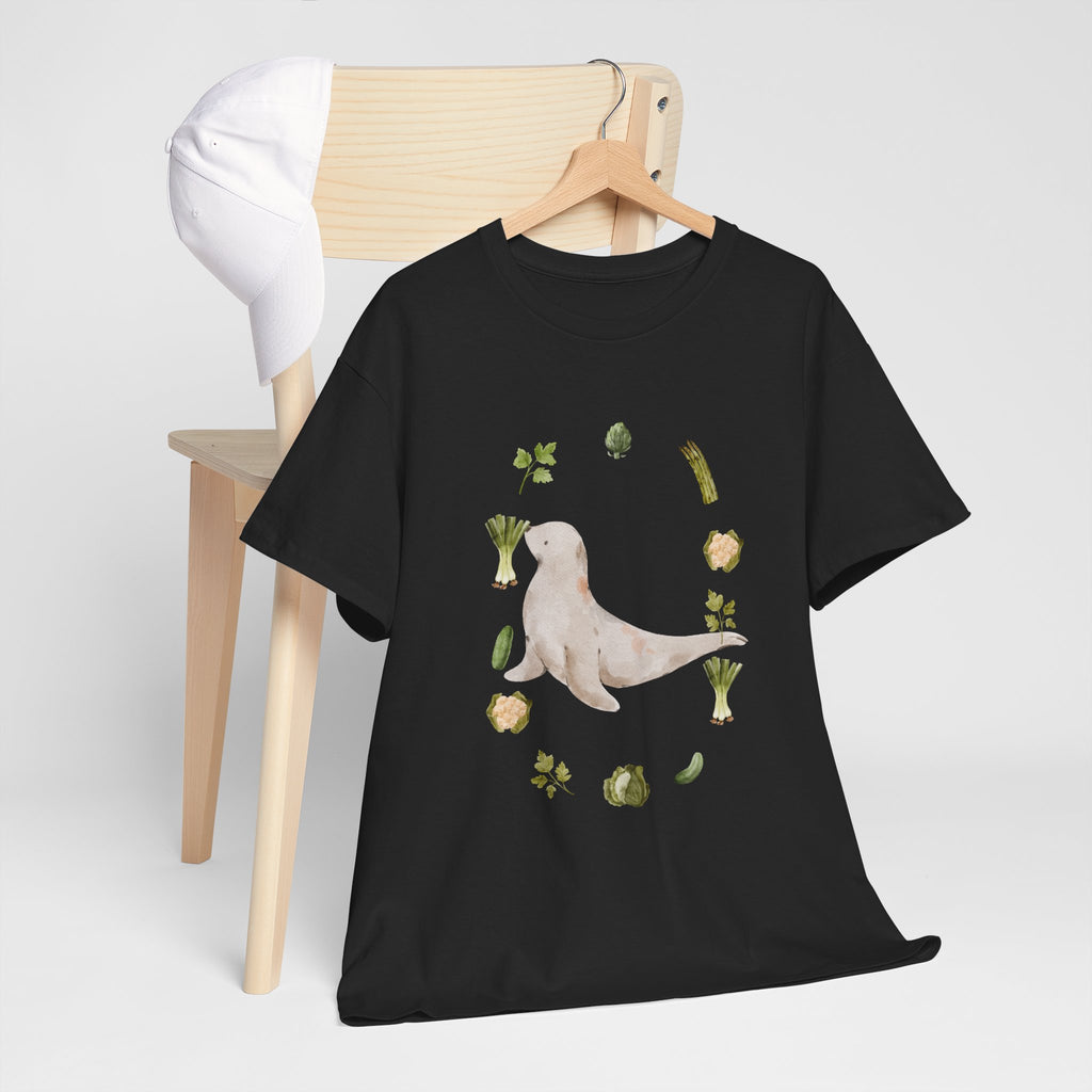A black t-shirt hanging on a chair, featuring a graphic design of a sea lion surrounded by green onions, cabbage, and broccoli.