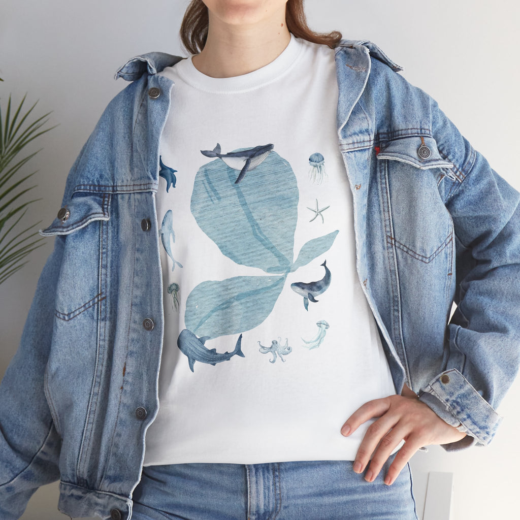 A girl wearing a denim jacket over a white t-shirt featuring a colorful design of a blue bloom surrounded by whales, jellyfish, and starfish.