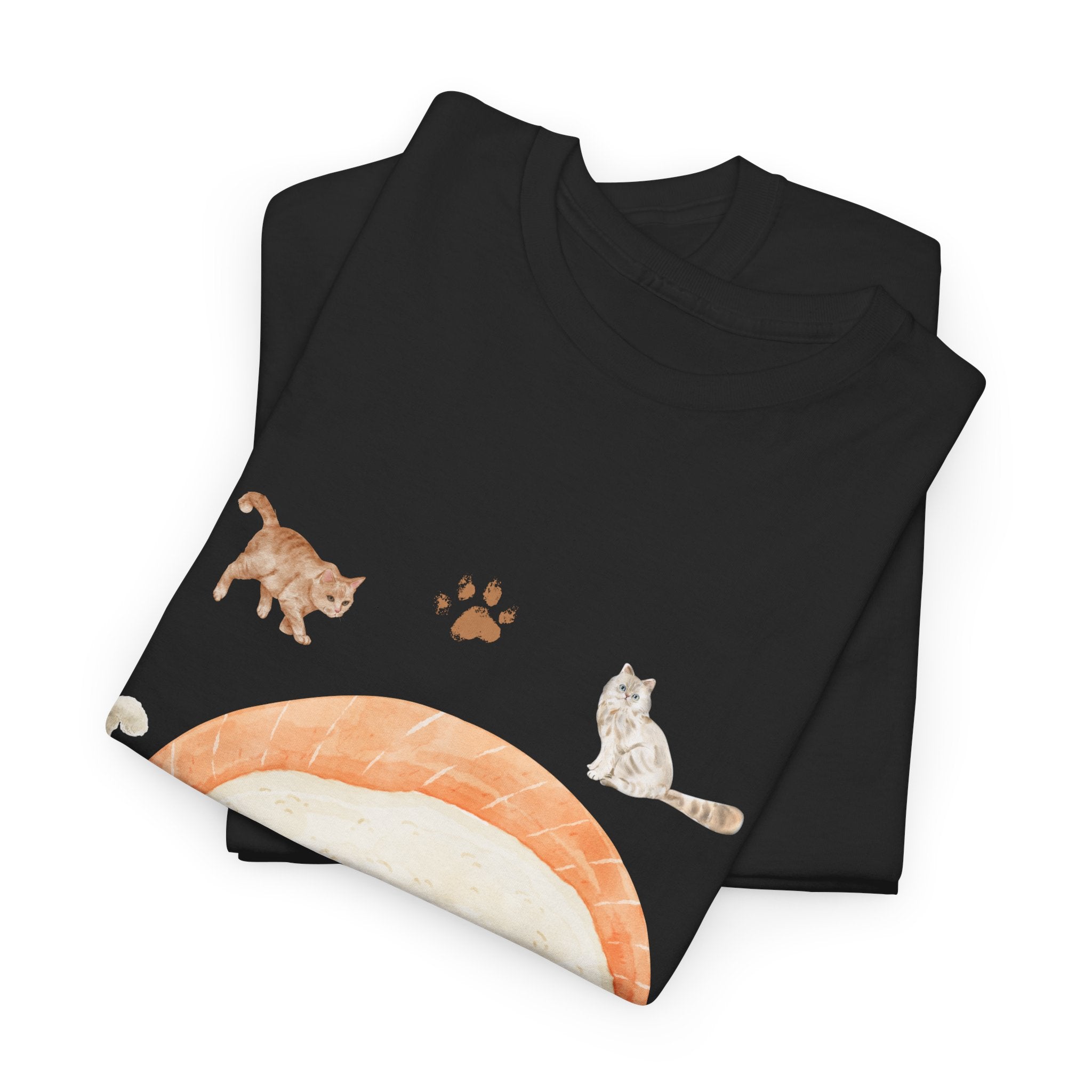 A folded black t-shirt featuring a graphic design of a piece of nigiri sushi surrounded by a circle of cats, yarn balls, and cushions.